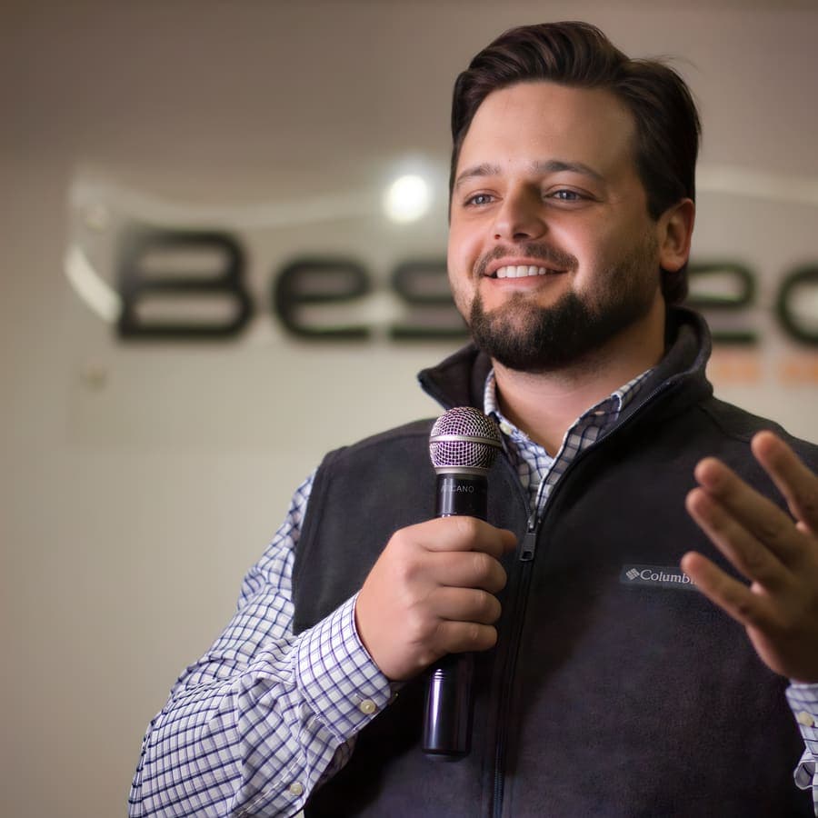 Aluno de colete gesticula ao microfone durante a apresentação
