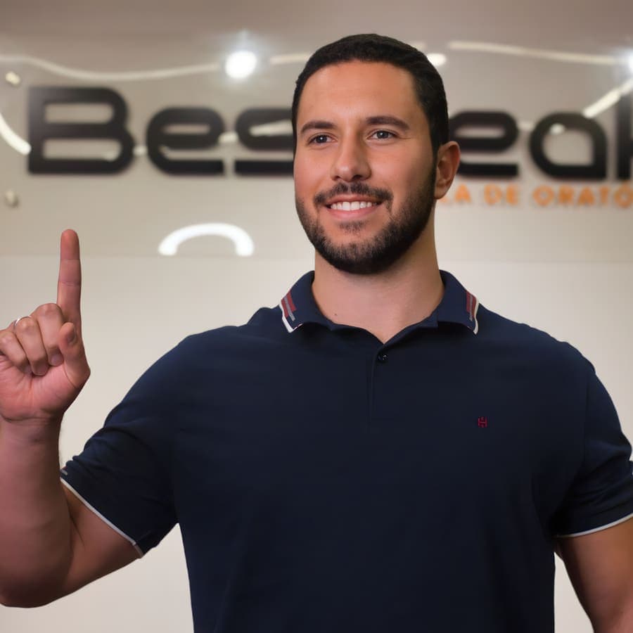 Aluno sorri no palco da Bespeak, levantando o dedo para marcar um ponto